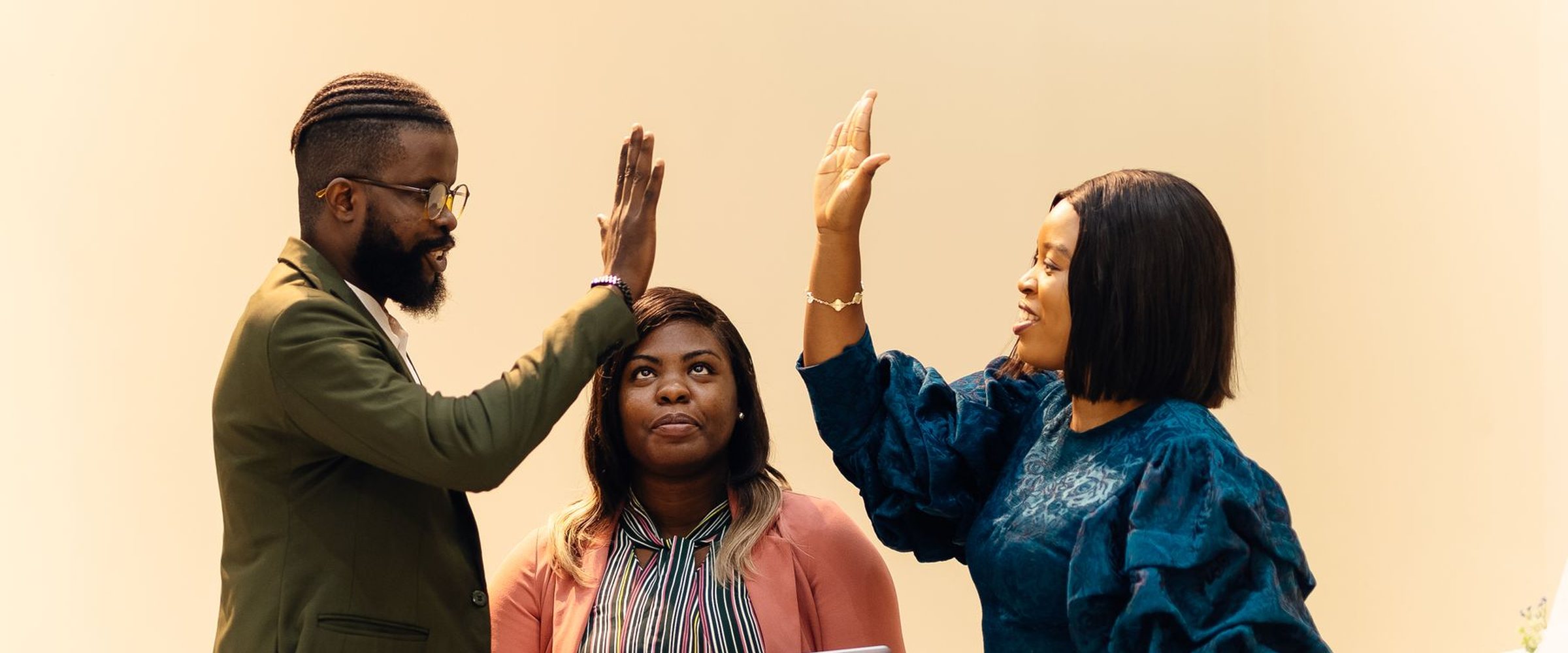 Three colleagues celebrate with a high five in a bright office